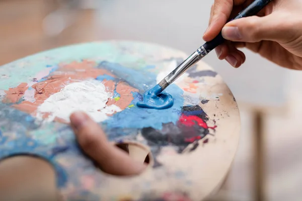 Vue recadrée de la femme mélangeant les couleurs sur la palette avec pinceau — Photo de stock