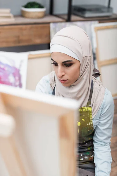 Araberin im Hidschab zeichnet zu Hause auf verschwommener Staffelei — Stockfoto