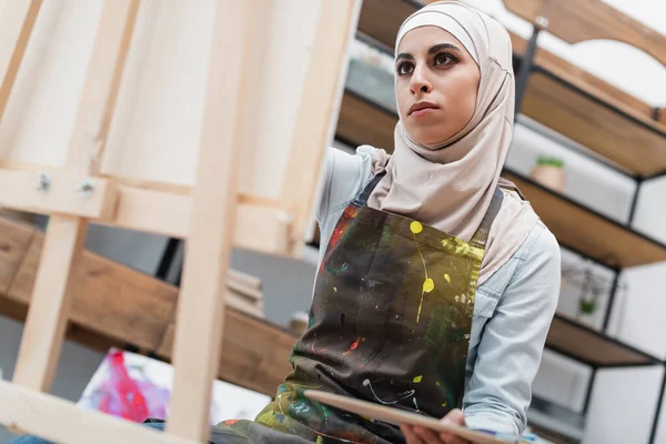 Low angle view of blurred muslim woman drawing on blurred easel at home — Stock Photo