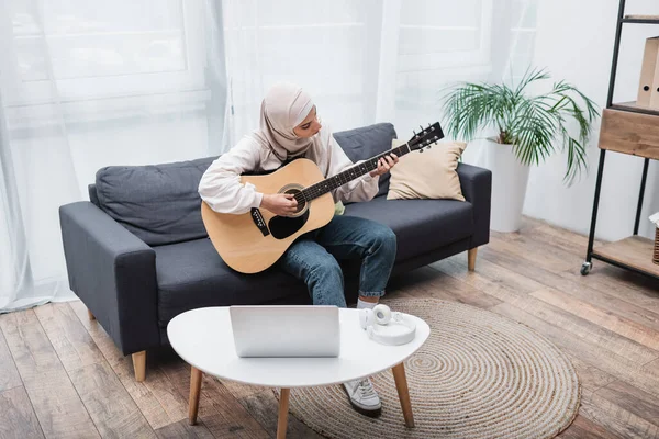 Arabe femme jouer de la guitare pendant la leçon vidéo sur ordinateur portable à la maison — Photo de stock