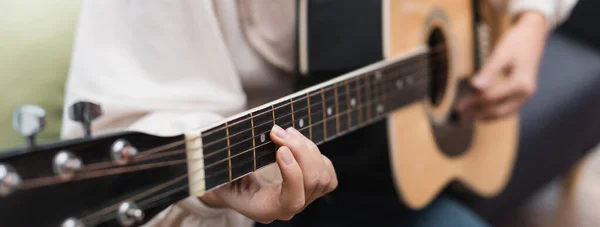 Partial view of blurred woman playing guitar at home, banner — Stock Photo