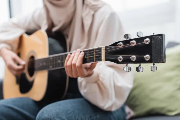 Vue recadrée de femme floue jouant de la guitare tout en étant assis à la maison — Photo de stock