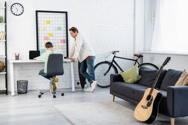 Homme souriant debout près de fils et ordinateur portable à la maison — Photo de stock