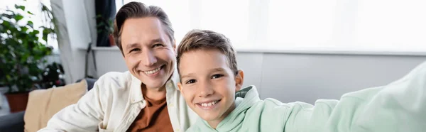 Positiver Mann blickt auf Kamera in der Nähe von Sohn zu Hause, Banner — Stockfoto