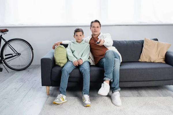 Family watching tv on couch in living room — Stock Photo