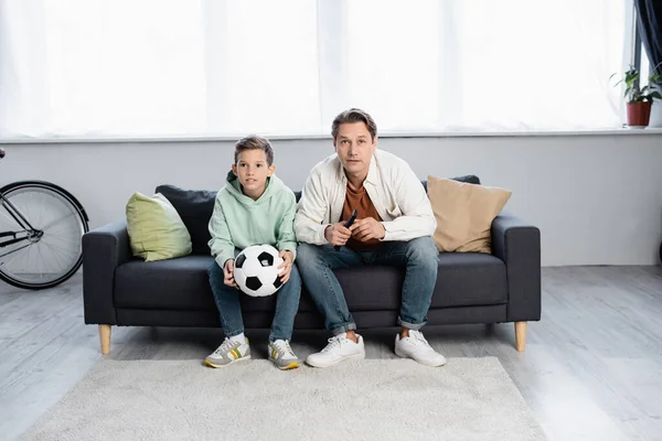 Father and boy with football watching tv at home — Stock Photo