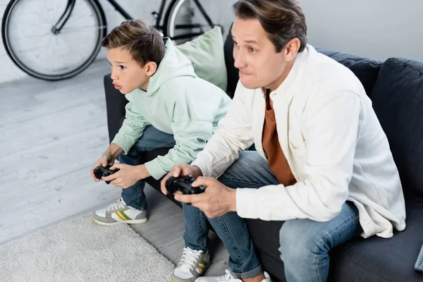 KIEW, UKRAINE - 11. OKTOBER 2021: Konzentrierter Junge beim Videospiel mit Papa zu Hause — Stockfoto