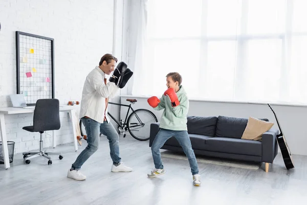 Padre e hijo en entrenamiento de guantes de boxeo en sala de estar - foto de stock