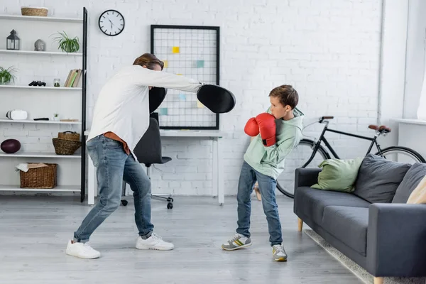 Préadolescent fils en gants de boxe formation avec papa à la maison — Photo de stock