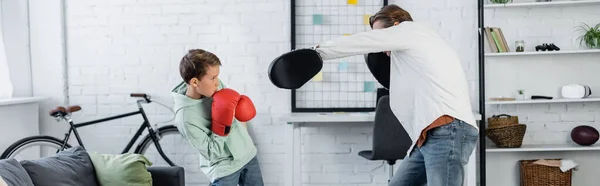 Man training with son in boxing gloves at home, banner — Stock Photo