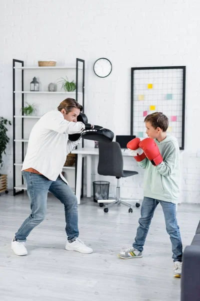 Enfant dans la formation de gants de boxe avec papa dans les tampons de poinçonnage à la maison — Photo de stock