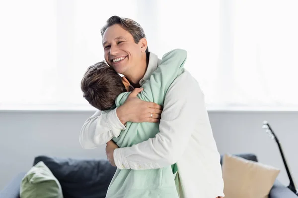 Man embracing preteen son in living room — Stock Photo