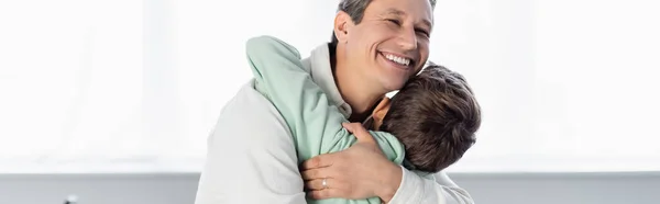 Uomo sorridente che abbraccia il figlio a casa, striscione — Foto stock