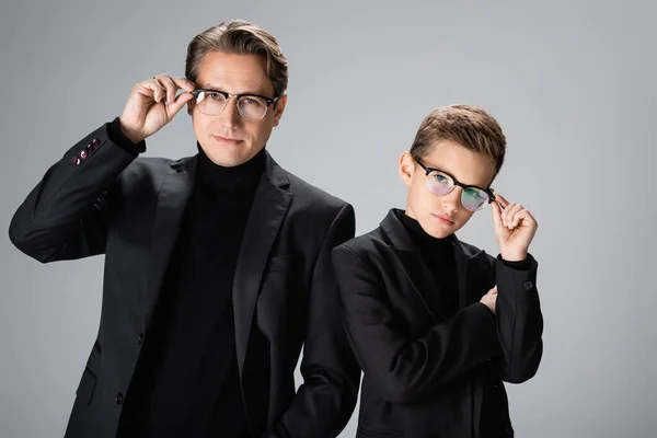 Father and boy in jackets holding eyeglasses isolated on grey — Stock Photo
