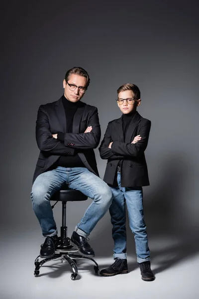 Stylish man posing on chair near son on grey — Stock Photo