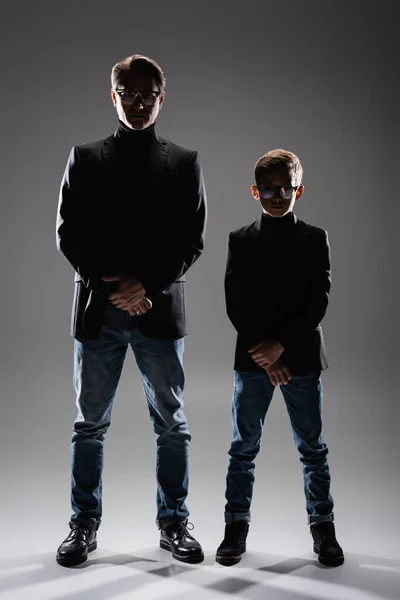 Тато і син в куртках і окулярах позує на сірий — стокове фото