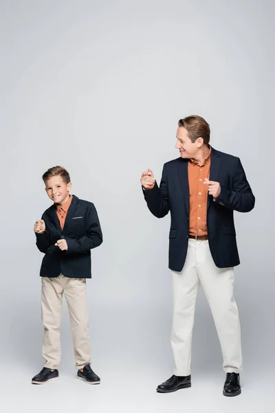 Full length of stylish father and son dancing on grey background — Stock Photo