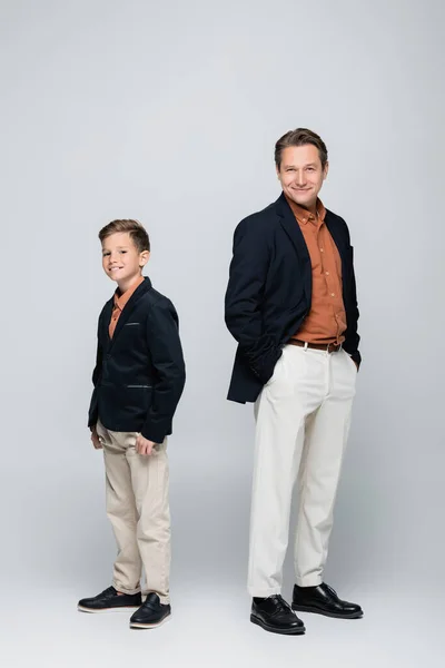 Trendy man posing near preteen son on grey background — Stock Photo