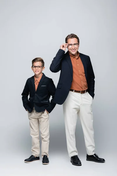 Cheerful boy in jacket posing near father on grey background — Stock Photo