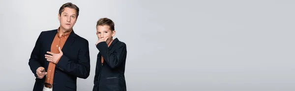 Schockierter Junge und Mann in Jacken blicken vereinzelt in die Kamera auf grauem Banner — Stockfoto