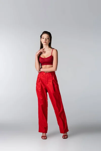 Toute la longueur du joli modèle en tenue rouge posant sur gris — Photo de stock