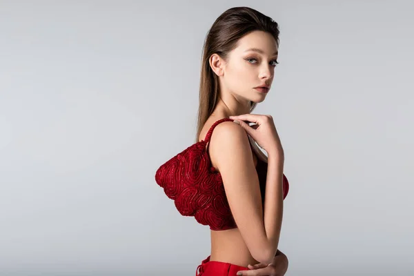 Junge Frau trägt rote stylische Tasche auf Schulter isoliert auf grau — Stockfoto