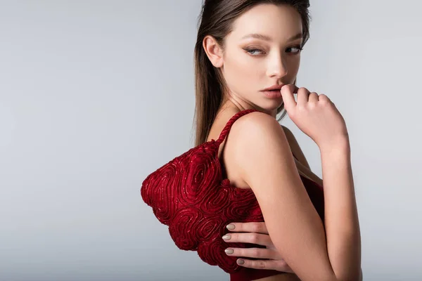 Mujer joven con bolso de moda rojo en el hombro aislado en gris - foto de stock