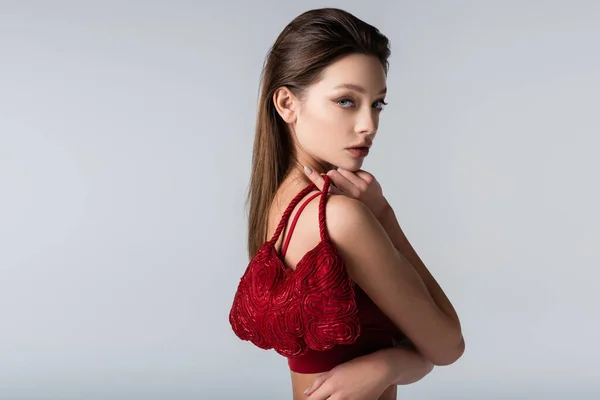 Giovane donna che tiene elegante borsa rossa isolata su grigio — Foto stock