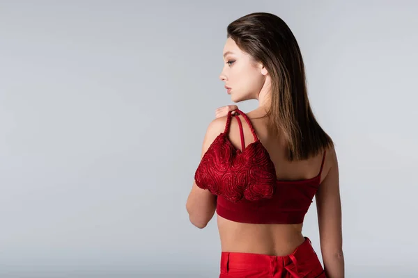Seitenansicht der jungen Frau mit roter stylischer Tasche isoliert auf grau — Stockfoto