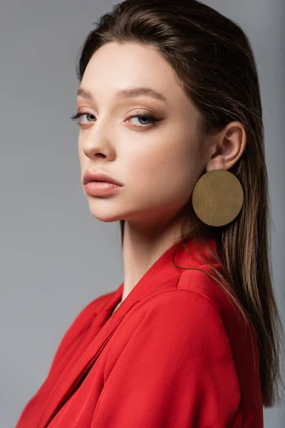 Stylische junge Frau im roten Blazer blickt vereinzelt in die Kamera auf grau — Stockfoto