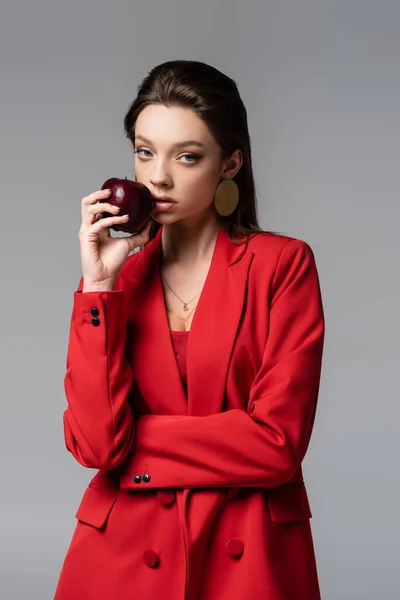 Young woman in red suit holding apple isolated on grey — Stock Photo