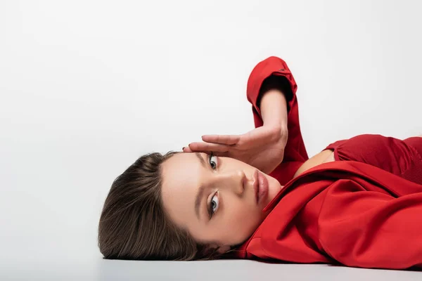 Trendy young woman in red blazer lying on grey — Stock Photo