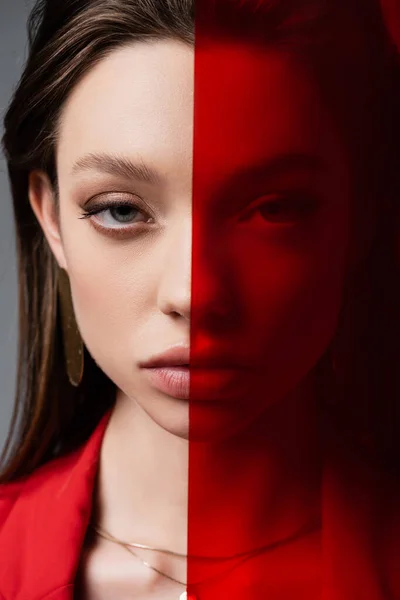 Close up of young woman looking at camera through red glass — Stock Photo