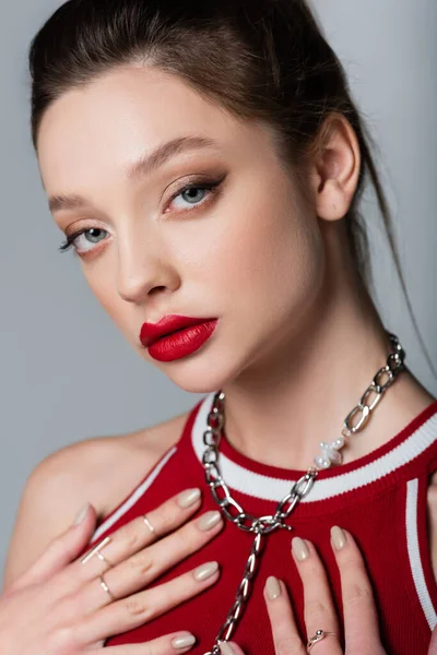 Mujer joven con labios rojos y cadena de collar aislado en gris - foto de stock