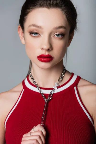 Joven bonita mujer con labios rojos tirando cadena collar aislado en gris - foto de stock