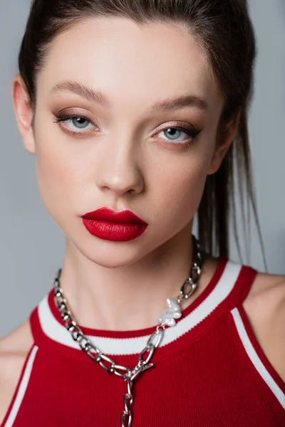 Jeune femme avec des lèvres rouges regardant la caméra isolée sur gris — Photo de stock