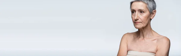 Femme d'âge moyen avec les épaules nues regardant loin isolé sur gris, bannière — Photo de stock