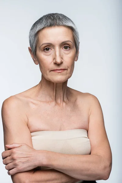 Donna di mezza età con spalle nude isolate su grigio — Foto stock