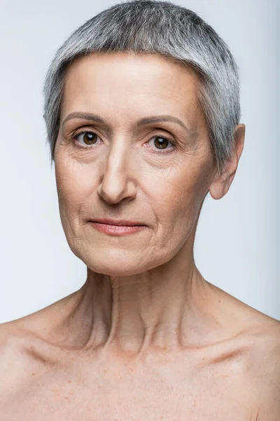 Primer plano de la mujer de mediana edad con el pelo gris aislado en gris - foto de stock