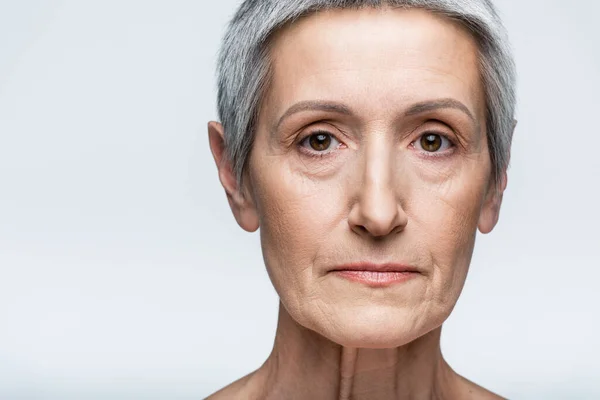Close up of mature woman with grey hair looking at camera isolated on grey — Stock Photo