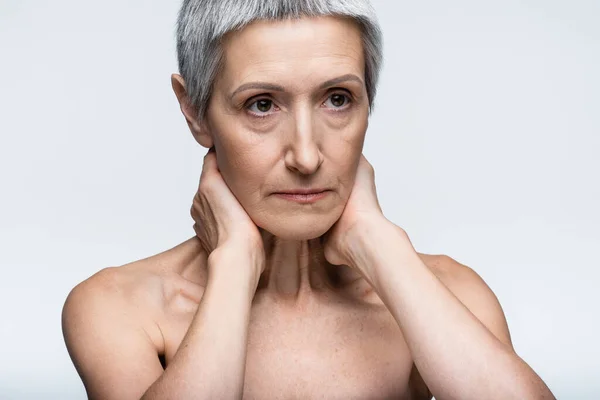 Femme mature aux épaules nues touchant le cou isolé sur gris — Photo de stock
