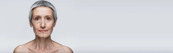 Mature woman with bare shoulders and marked lines on face looking at camera isolated on grey, banner — Stock Photo
