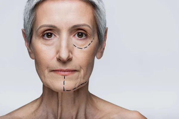 Middle aged woman with marked lines on face looking at camera isolated on grey — Stock Photo