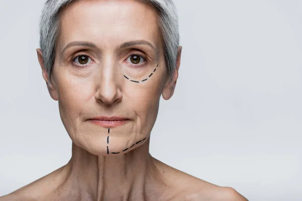 Femme d'âge moyen avec des lignes marquées sur le visage regardant la caméra isolée sur le gris — Photo de stock