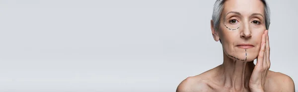 Donna matura con rughe e linee marcate che toccano il viso isolato su grigio, banner — Foto stock