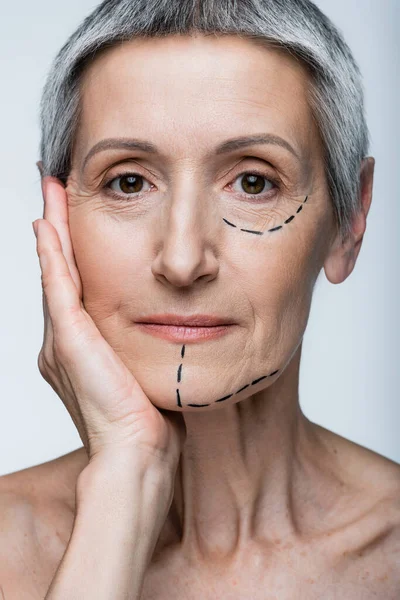 Close up of mature woman with marked lines on face looking at camera isolated on grey — Stock Photo