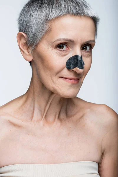 Cheerful middle aged woman with black patch on nose isolated on grey — Stock Photo