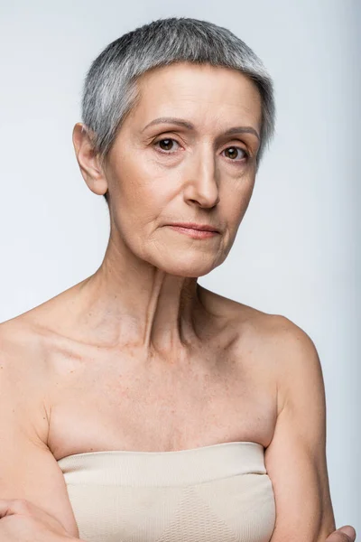 Mature woman with grey hair and wrinkles isolated on gray — Stock Photo