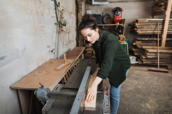 Carpenter working with plank and jointer machine in workshop — Stock Photo