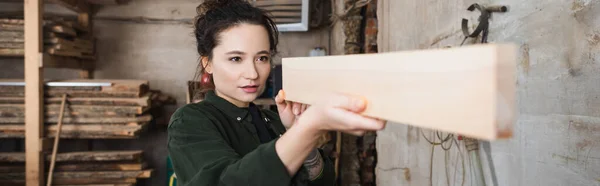 Carpenter checking wooden plank in workshop, banner — Stock Photo